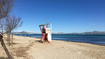Ein Rettungsturm am Strand, mit blauem Himmel und Bergen im Hintergrund.
