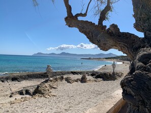 A beach with a rocky foreground and a clear view of the sea and distant mountains. - Holiday Home 'Playa Y Relax' with Private Terrace, Wi-Fi and Air Conditioning (Can Picafort)