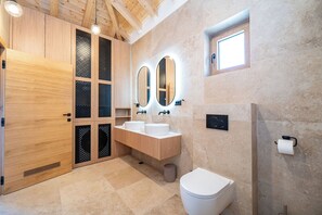 Une salle de bain moderne avec des meubles en bois, deux lavabos, des toilettes et un espace douche.