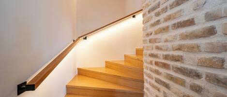 A wooden staircase with a brick wall on one side.