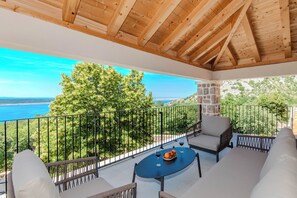 Un balcon avec vue sur la mer, un plafond en bois et un espace salon extérieur.