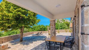 Eine Terrasse im Freien mit Tisch und Stühlen, einer Steinmauer und einem Baum.