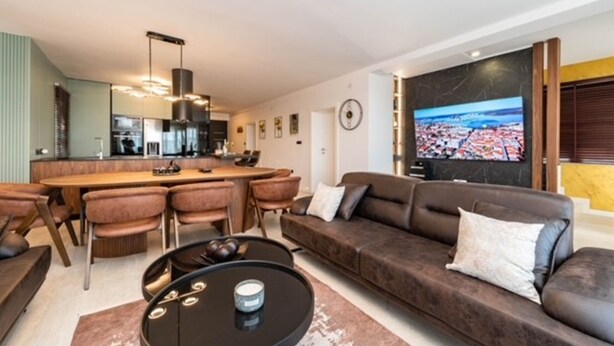 Een moderne woonkamer met een bank, een salontafel en een tv waarop een stadsgezicht te zien is.