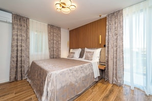 A modern bedroom with a large bed, wooden panel wall, and a ceiling light fixture. - Villa Morea (Sukosan)