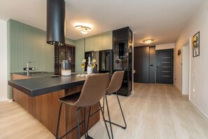 A modern kitchen with a central island, bar stools, a built-in oven, and a refrigerator. - Villa Morea (Sukosan)