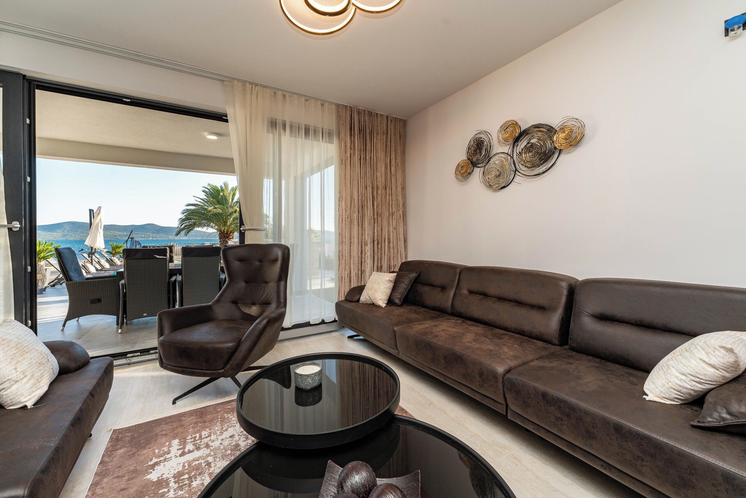 A modern living room with a sofa, armchair, and a glass coffee table.