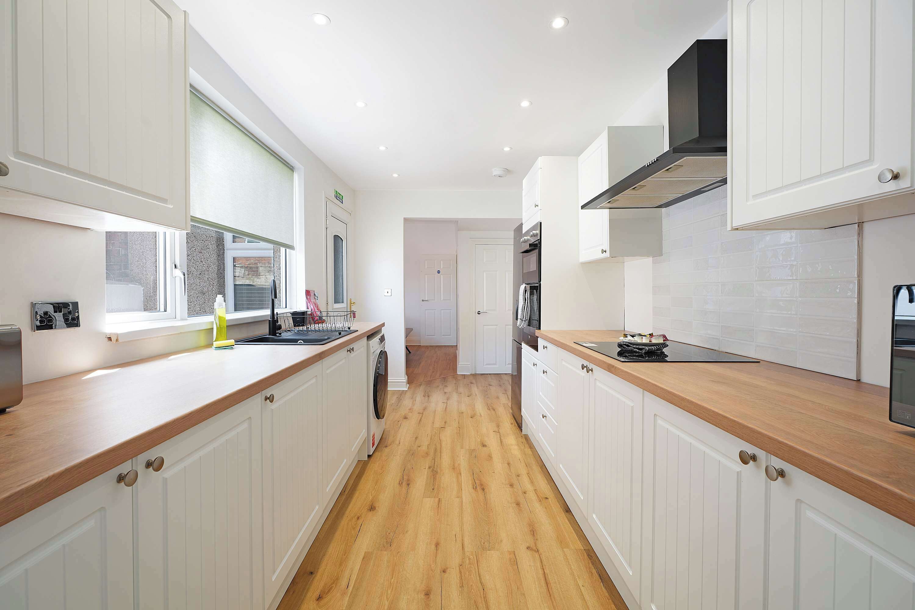 A modern kitchen with white cabinetry, wooden countertops, and a central island.