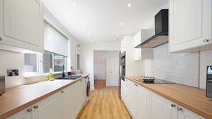 Una cocina moderna con armarios blancos, encimeras de madera y una isla central.