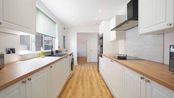 A modern kitchen with white cabinetry, wooden countertops, and a central island.