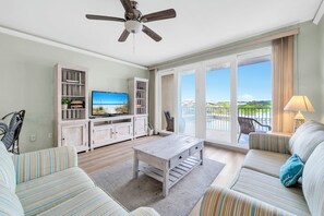 A spacious living room with a television, a ceiling fan, a sofa, a coffee table, and a balcony with a view. - ☀️Close to Beach, Lake Views-Laketown Wharf 329☀️ (Panama City Beach)