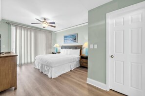 A hotel room with a bed, bedside lamps, a ceiling fan, a painting on the wall, and a door. - ☀️Close to Beach, Lake Views-Laketown Wharf 329☀️ (Panama City Beach)