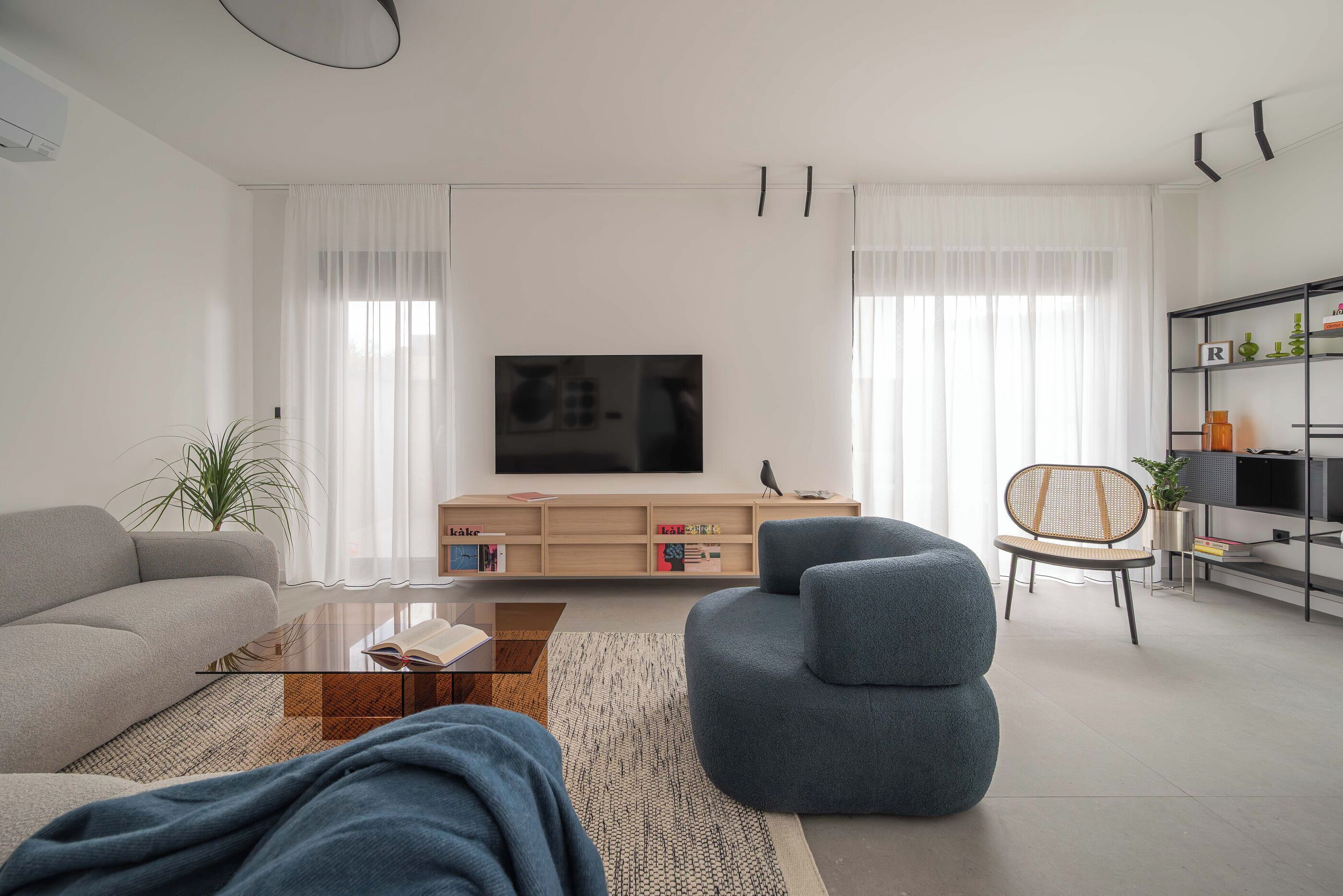A modern living room with a sofa, armchair, coffee table, and TV.
