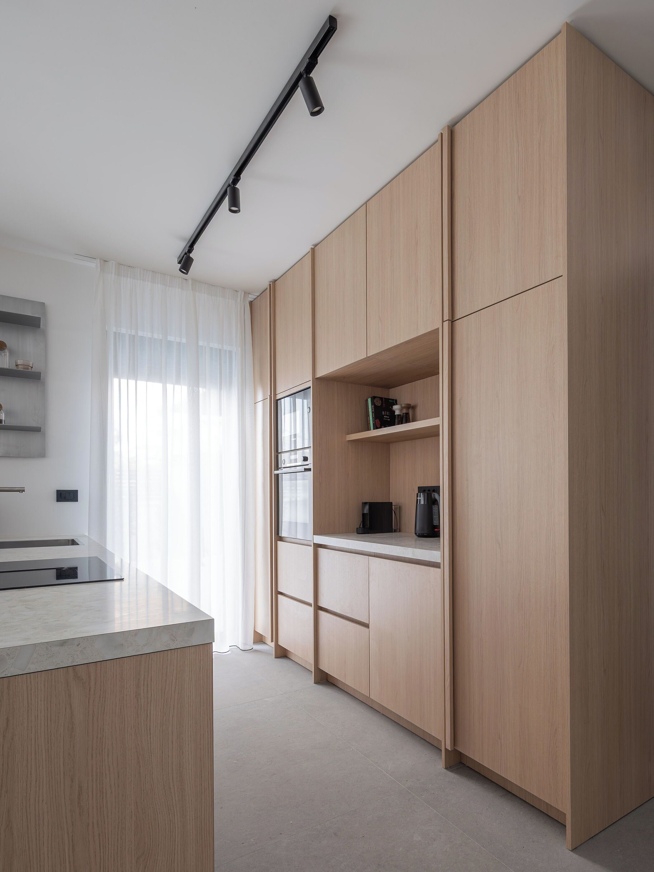 A modern kitchen with wooden cabinets, a countertop, and a built-in oven.