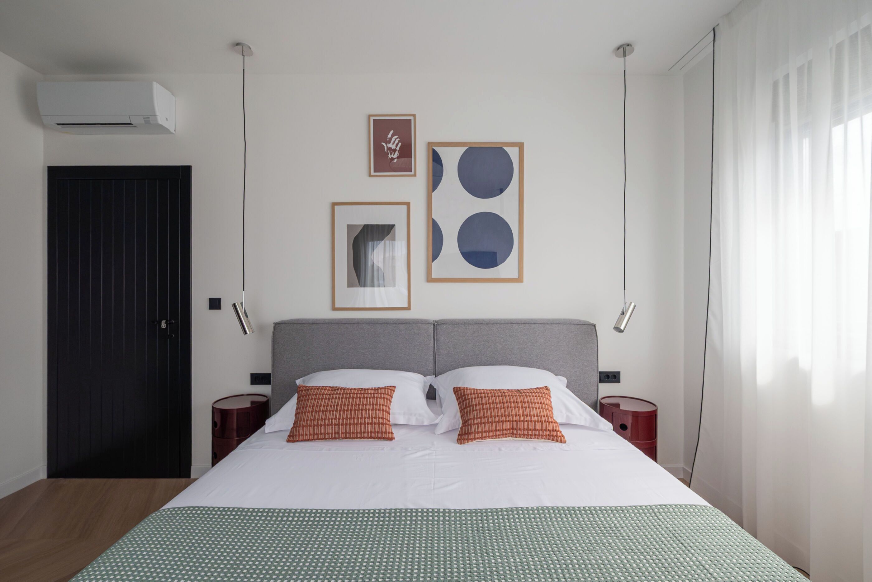 Ein Hotelzimmer mit einem Bett, zwei Nachttischen, einem Kleiderschrank und Wandbildern.