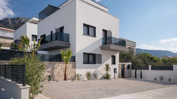 A modern two-story building with balconies, a stone wall, and a paved driveway. - Villa Respiro Residence South (Kastela)