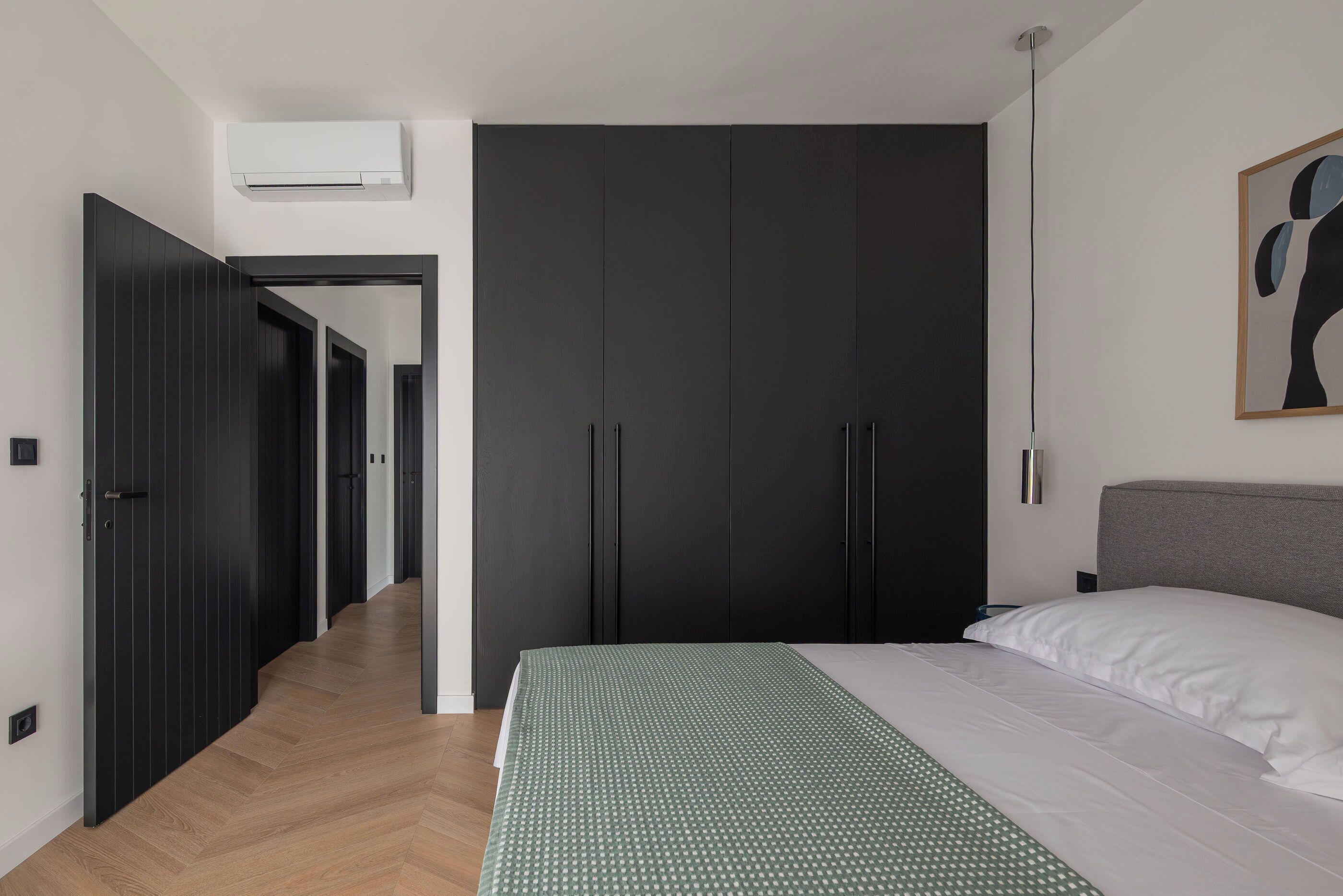 A bedroom with a bed, a wardrobe, and a hallway.
