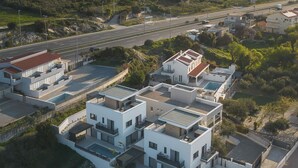 A residential area with modern buildings, a road, and a mountainous backdrop. - Villa Respiro Residence South (Kastela)