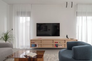 Un salon moderne avec un téléviseur à écran plat, une bibliothèque, un canapé et une table basse.