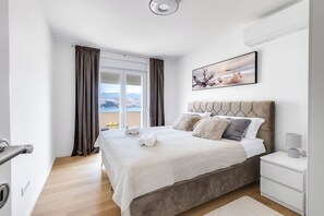 Una habitación de hotel con una cama, una mesita de noche, una ventana con cortinas y un cuadro en la pared.