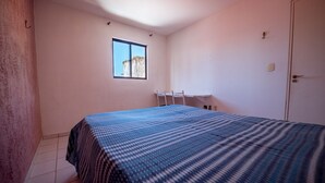 A bedroom with a bed, a window, a desk, and a door. - Apto c 3 Quartos e Garagem a 260 m da Praia (João Pessoa)