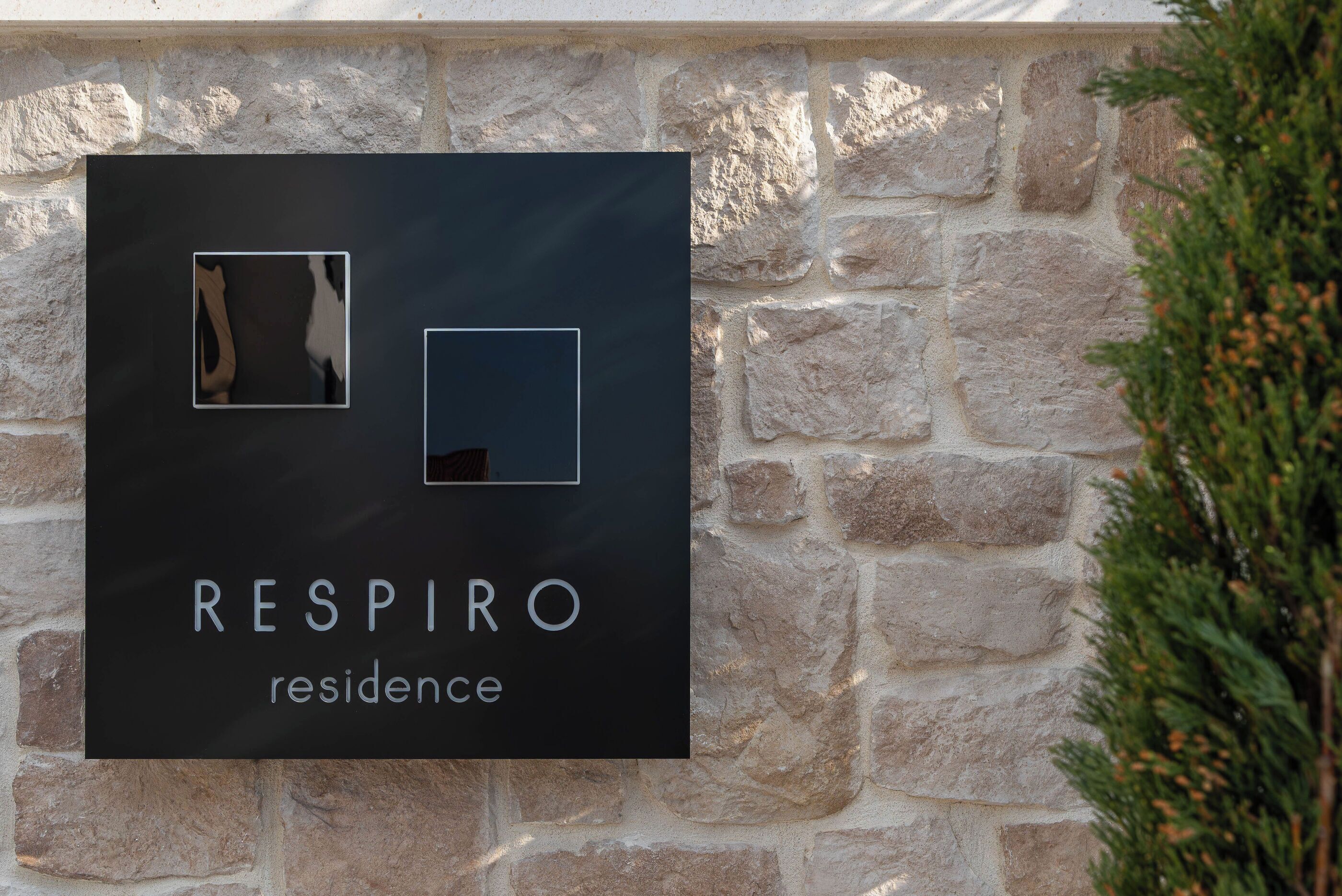 A sign with the text 'RESPIRO residence' on a stone wall.
