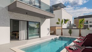 Ein moderner Poolbereich mit klarem Wasser, Liegestühlen und einer Glasbrüstung.