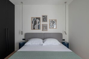 A modern hotel room with a large bed, two bedside tables, a grey headboard, and four framed artworks on the wall. - Villa Respiro Residence North (Kastela)