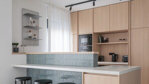Eine moderne Küche mit einer zentralen Kochinsel, Barhocker, Holzschränken und integrierten Geräten.