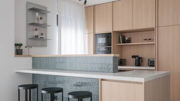 Eine moderne Küche mit einer zentralen Kochinsel, Barhocker, Holzschränken und integrierten Geräten.