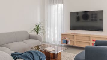 Ein modernes Wohnzimmer mit einer Couch, einem Couchtisch, einem Fernseher und einem Bücherregal.