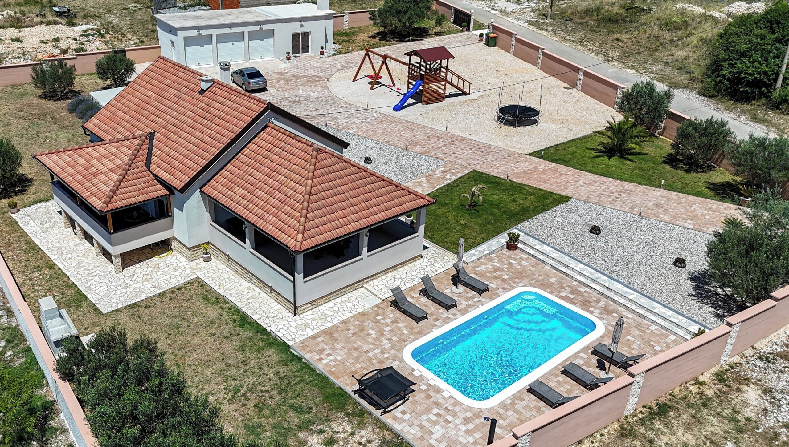 Una casa moderna con piscina, area giochi e garage.