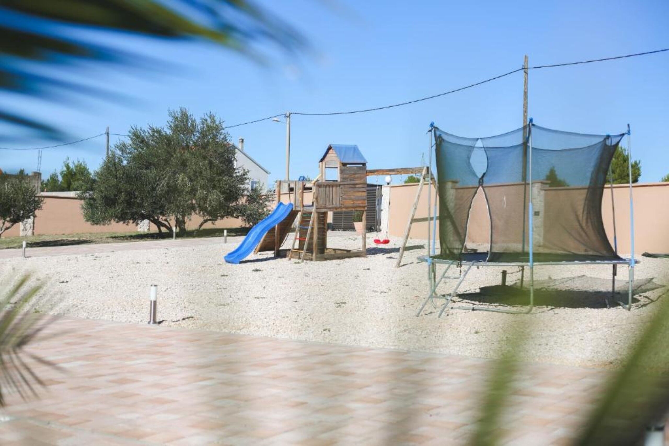 A playground with a slide, climbing structures, and a trampoline.