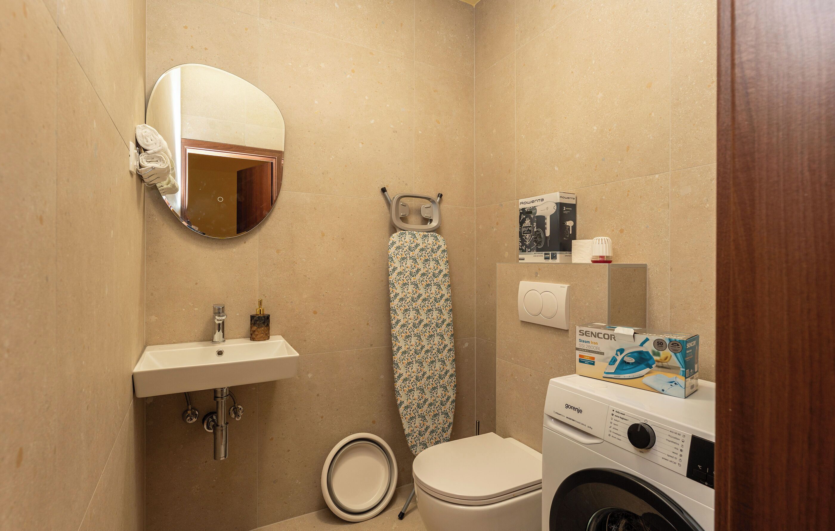Une petite salle de bain comprenant un lavabo, des toilettes, un miroir et un lave-linge.