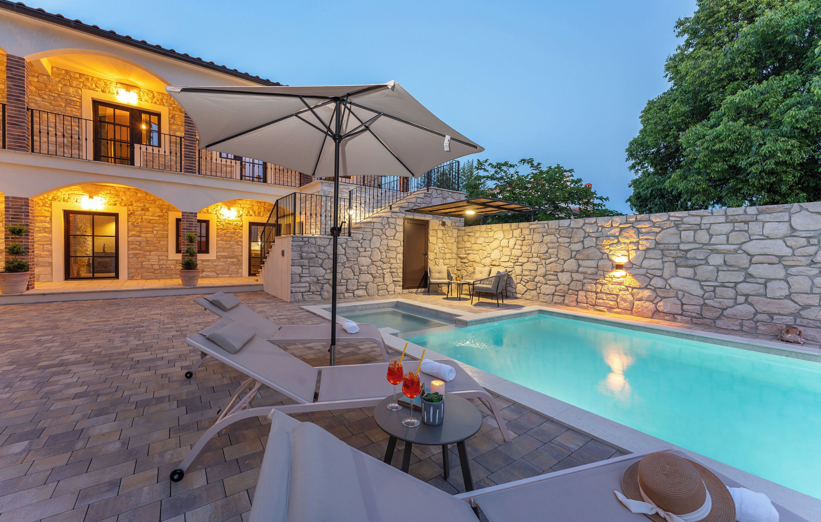 A poolside area with lounge chairs, a table with drinks, and a large umbrella.