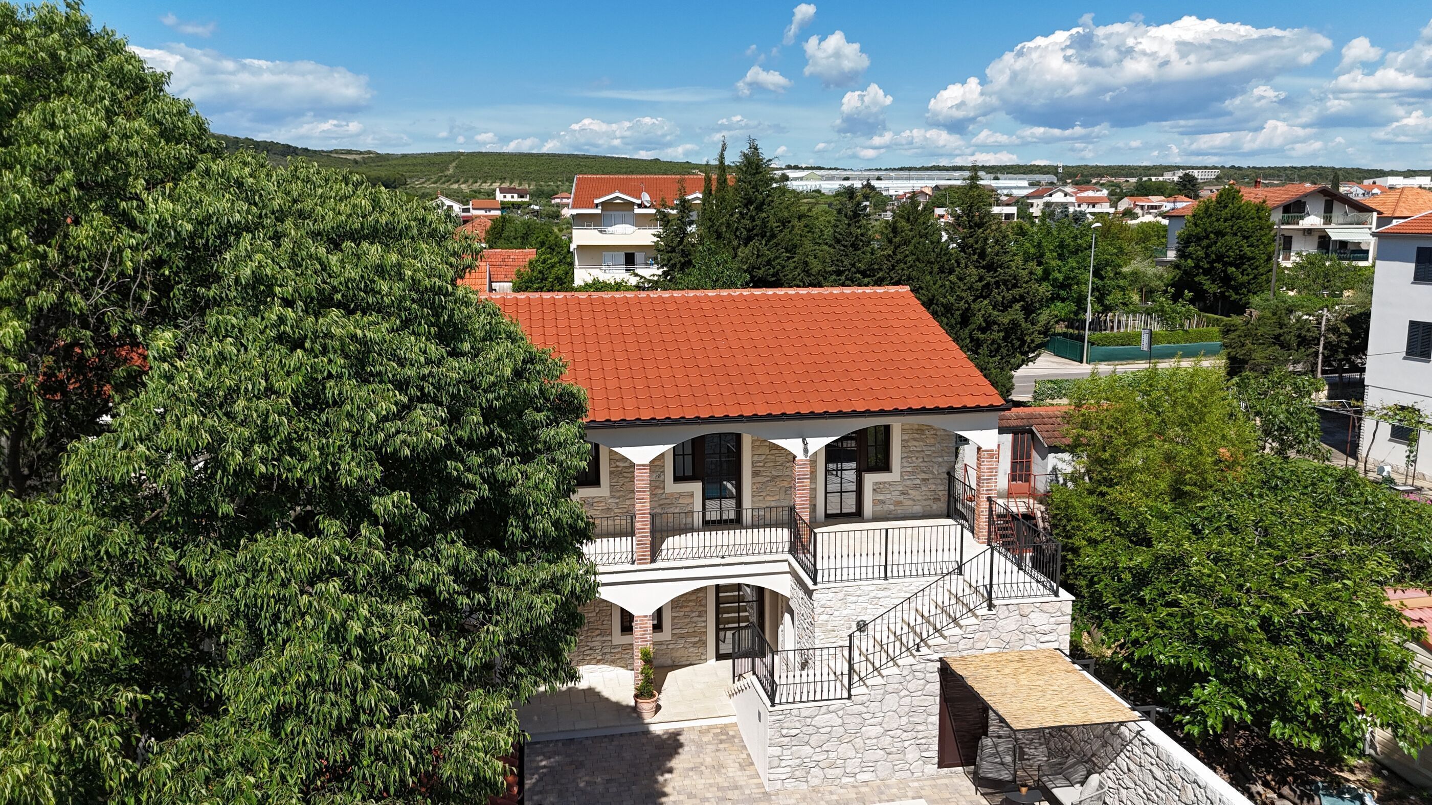 Ein Gebäude mit rotem Ziegeldach, Steinmauern und einem Balkon mit Metallgeländer.