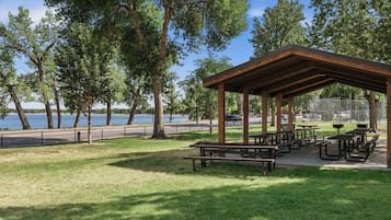A park with picnic tables and a covered pavilion overlooking a body of water.