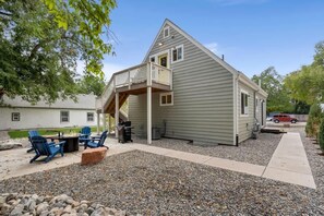 A house with a covered patio, outdoor seating, and a gravel driveway. - Renovated Executive Rental Near CSU (Fort Collins)