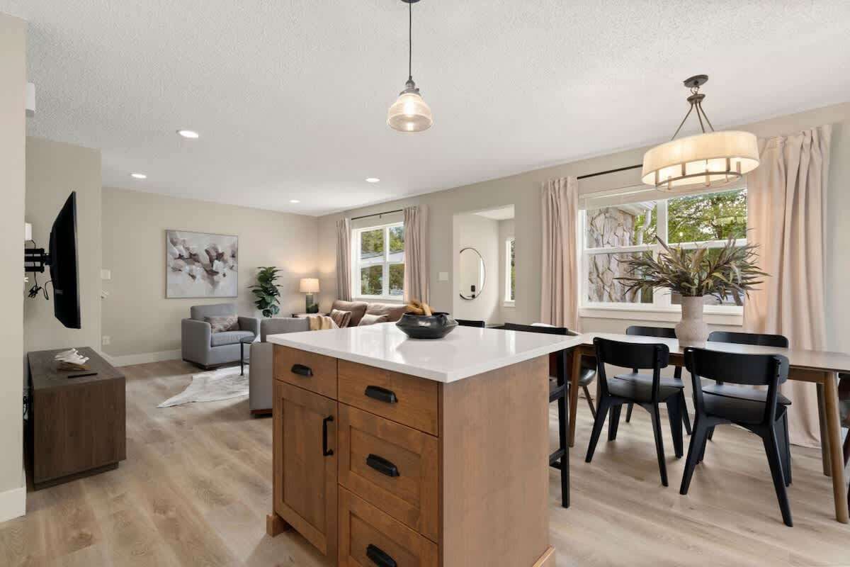 Une cuisine moderne avec un îlot central, des meubles en bois et des chaises noires.