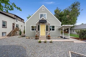 A two-story house with a stone facade, a yellow front door, and a covered porch. - Renovated Executive Rental Near CSU (Fort Collins)
