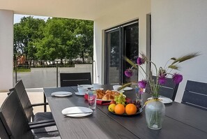 An outdoor dining table with plates, cutlery, and a fruit basket. - Villa Tara (Medulin)