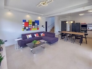 A modern living room with a sofa, coffee table, and a dining area with a table and chairs. - Villa Tara (Medulin)