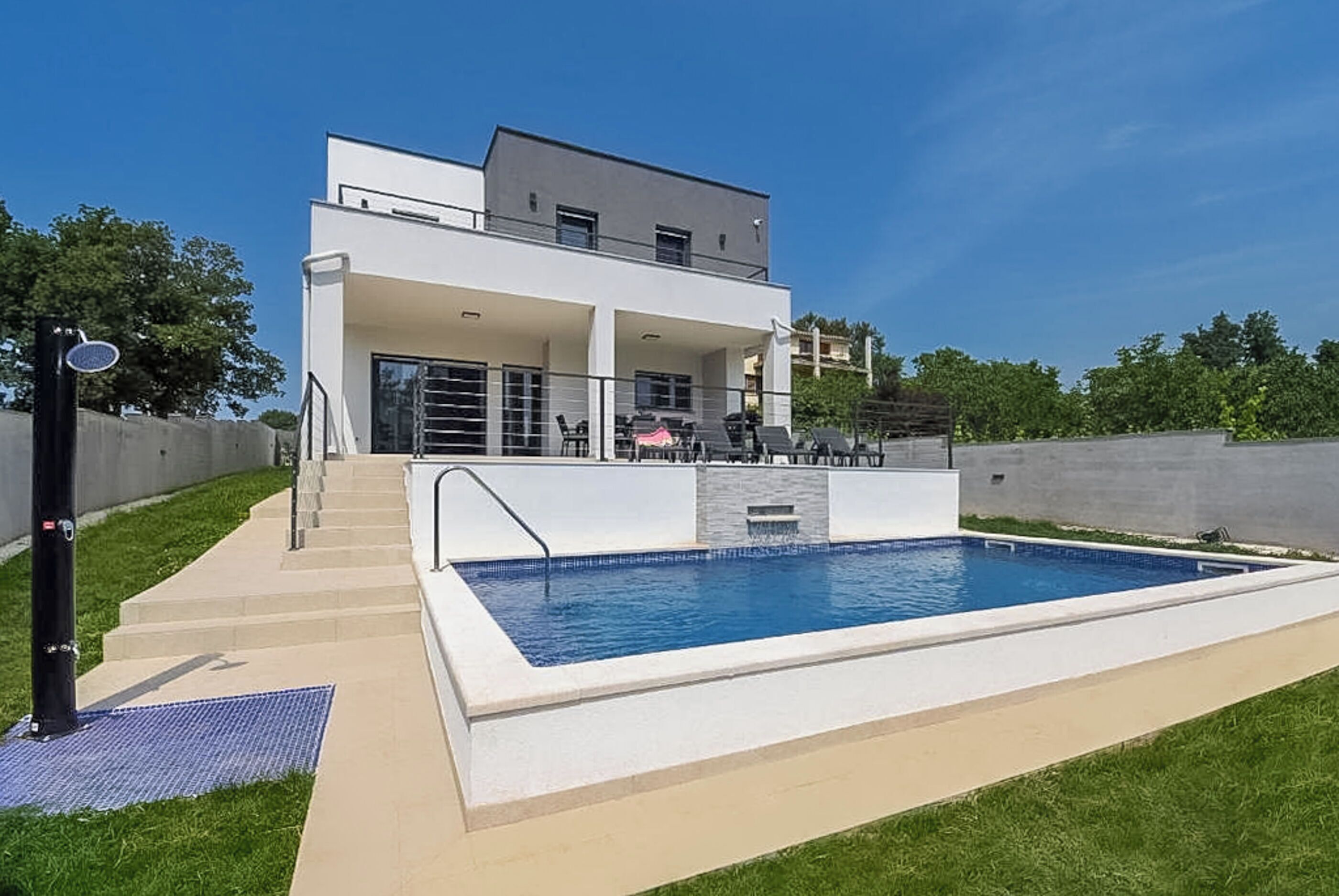 A modern two-story house with a swimming pool, outdoor seating, and a covered patio.