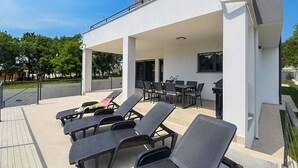 Un espacio al aire libre techado con sillones, una mesa y una parrilla.