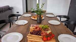 Una mesa de madera para comer con platos, una decoración central y diversos alimentos.