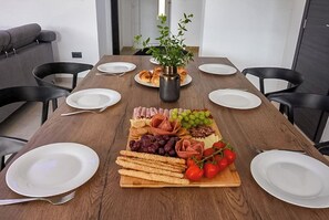 A wooden dining table with plates, a centerpiece, and a variety of food items. - Villa Tara (Medulin)