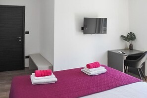 A hotel room with a bed, a desk, a chair, a TV, and a plant. - Villa Tara (Medulin)