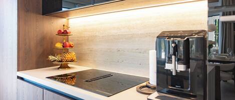 A modern kitchen with a built-in coffee machine, a fruit display, and a sleek countertop.