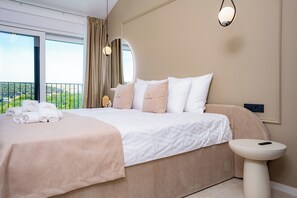 Habitación de hotel con una cama grande, una mesita de noche, vistas al exterior y una ventana con cortinas.