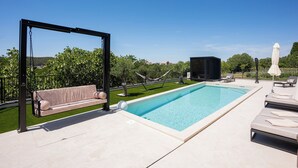 A swimming pool with a swing chair, lounge chairs, and a hammock. - Villa Loparia (Lopar)
