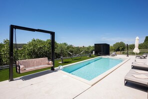 A swimming pool with a swing chair, lounge chairs, and a hammock. - Villa Loparia (Lopar)